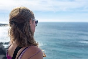 Jovem Mulher Com Longos Cabelos Loiros Sentada Na Praia E Olhando Para O Horizonte Oceano Azul E Cos.jpeg